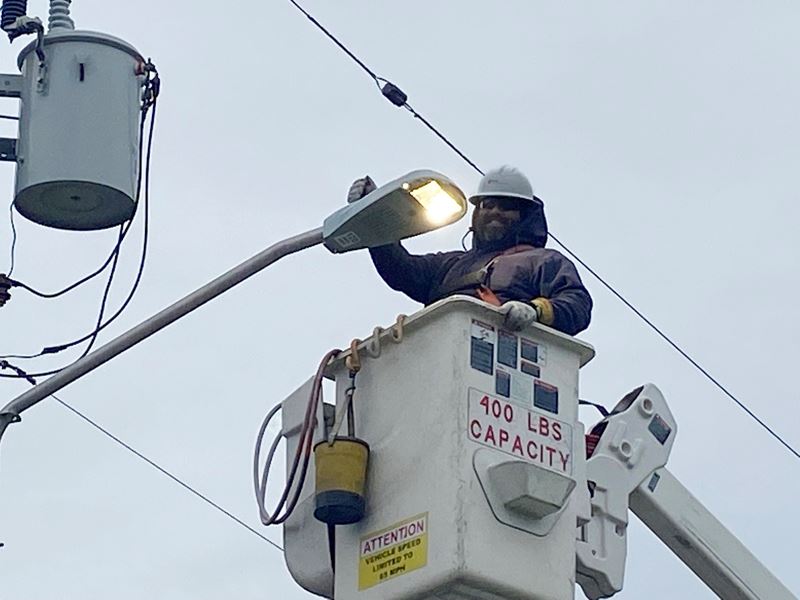 A man in a hard hat in a lift bucket turns on an LED street light