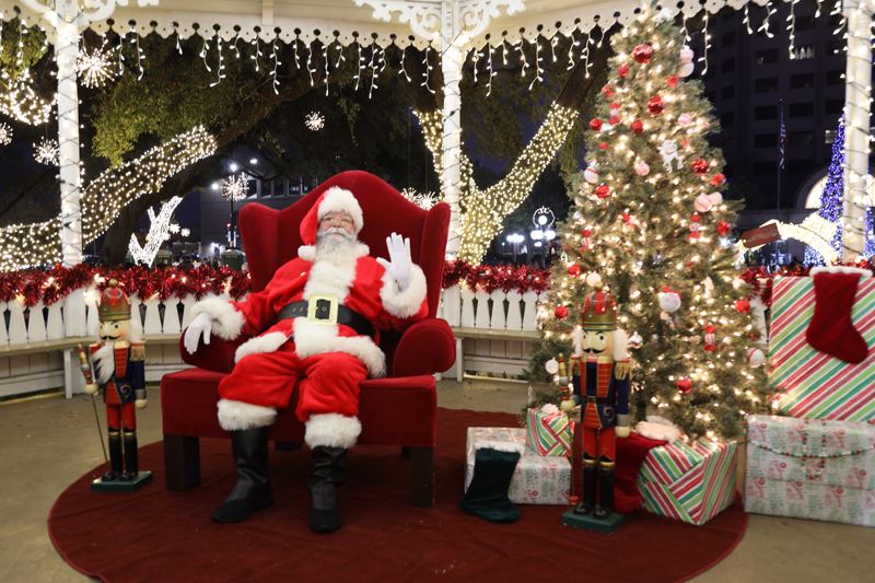 Santa sits in a chair in the DeLeon Plaza gazebo next to a Christmas tree