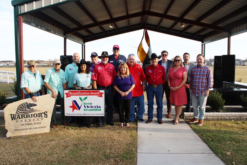 Large group photo in front of a pavilion with a Warrior's Weekend sign and a KVB sign