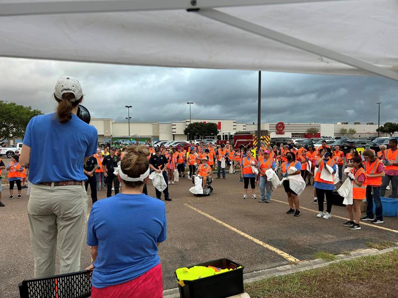 A woman with a megaphone addresses a crowd of people in safety vests