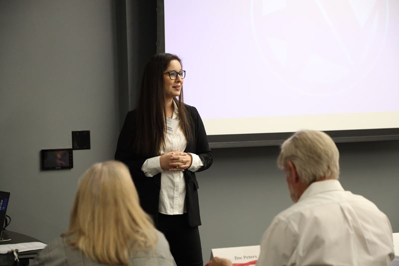 Woman stands in front of a classroom and gives a presentation
