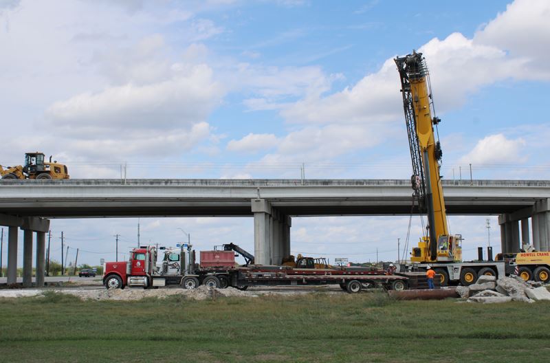 A crane and other construction equipment operate at the Loop 463 overpass on Houston Highway