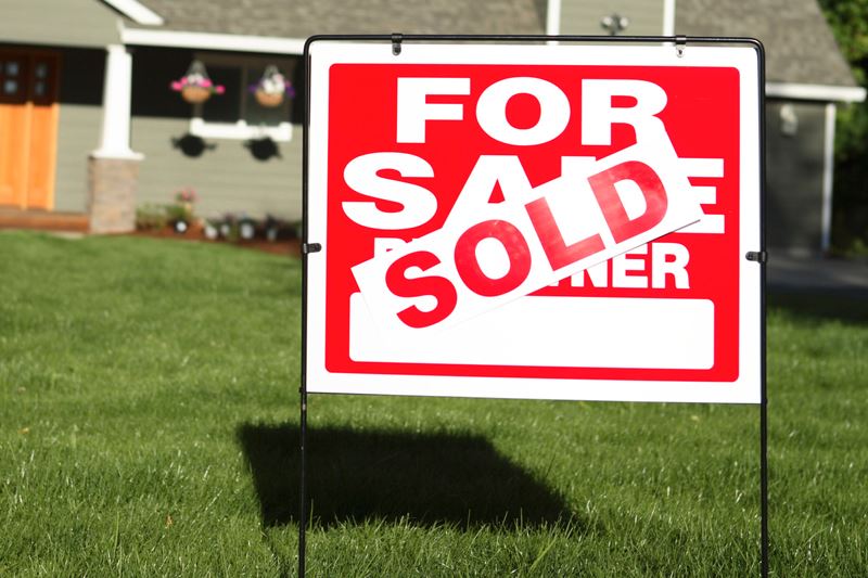 A for sale sign in front of a home with a sold sign plastered over it