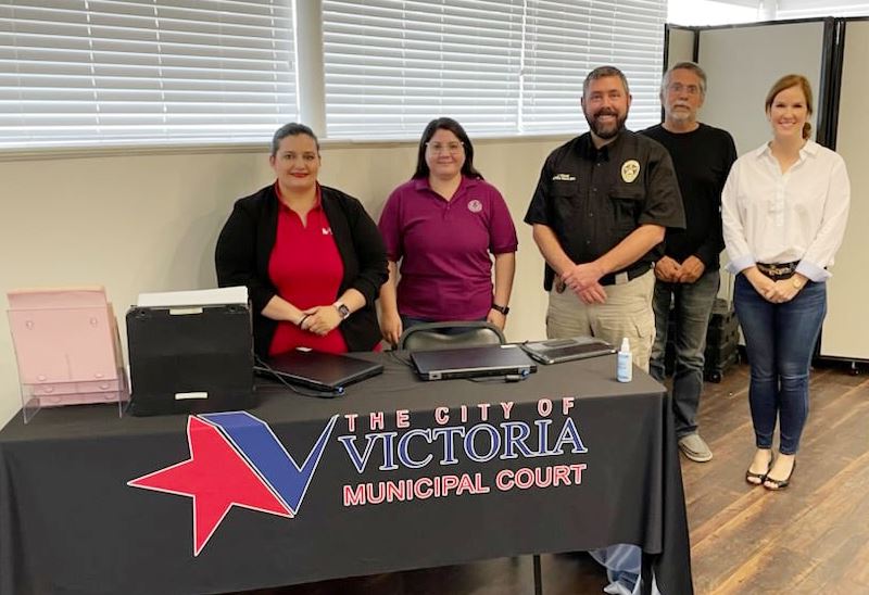 People smiling and standing around a Municipal Court table.