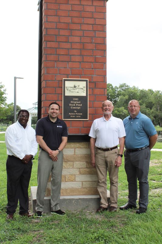 Group photo with plaque with image of duck pond: Original duck pond concept by Nylece Putnam