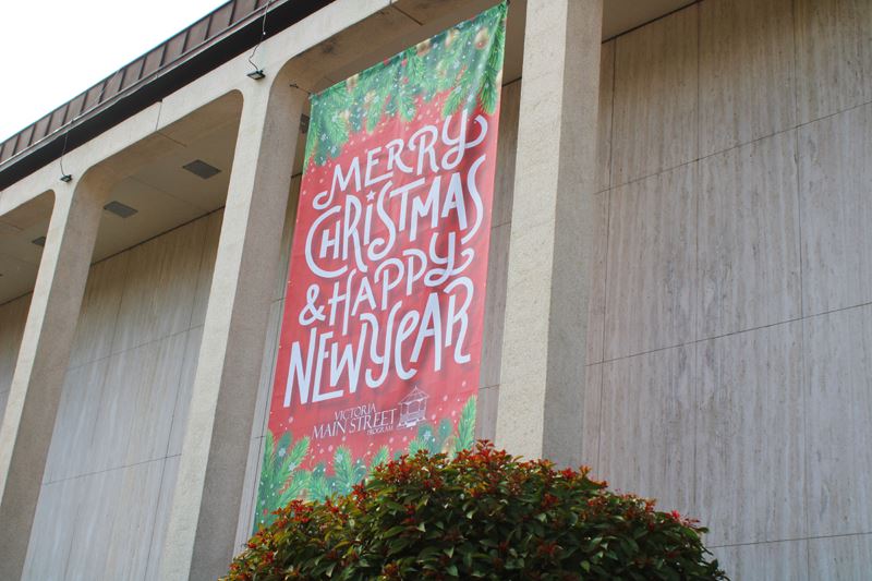 Large banner hanging from City Hall columns reading Merry Christmas and Happy New Year