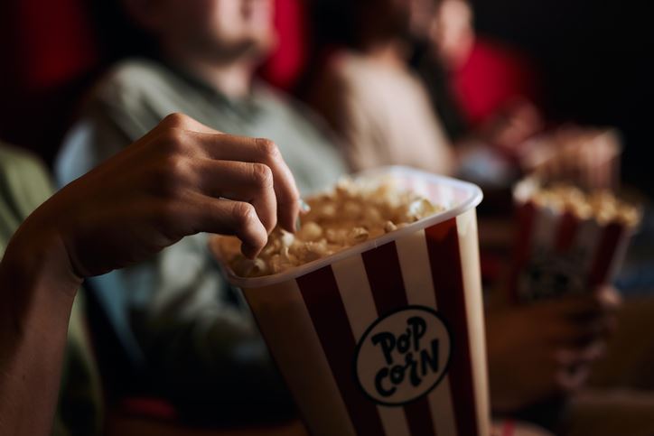 Close up of a person eating popcorn in a movie theater