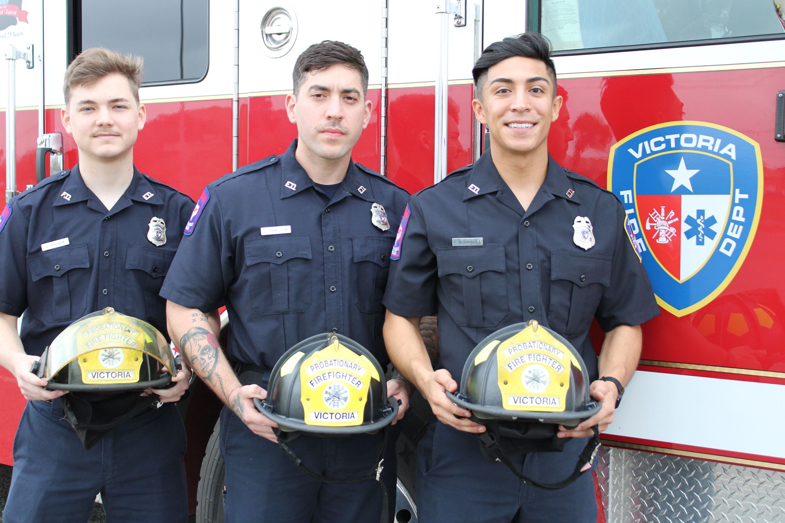EMT firefighter trainees with helmets in front of fire truck