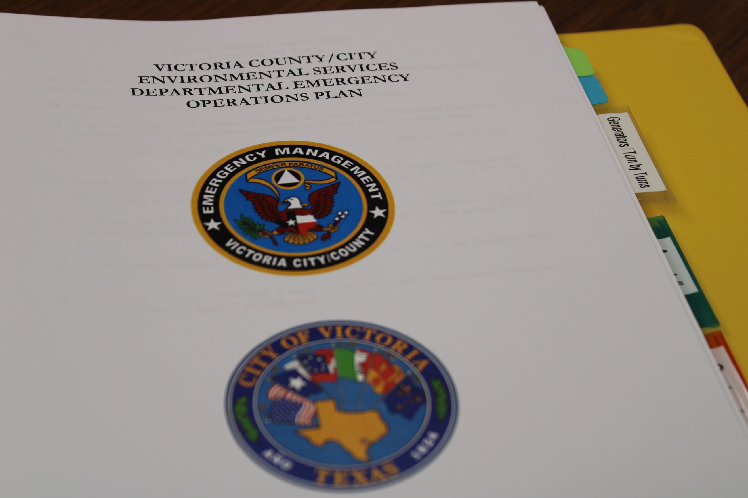 Yellow binder open to page displaying City and Office of Emergency Management logos