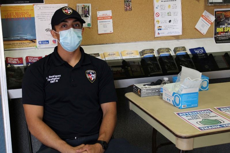 Firefighter EMT sits at table with box of masks