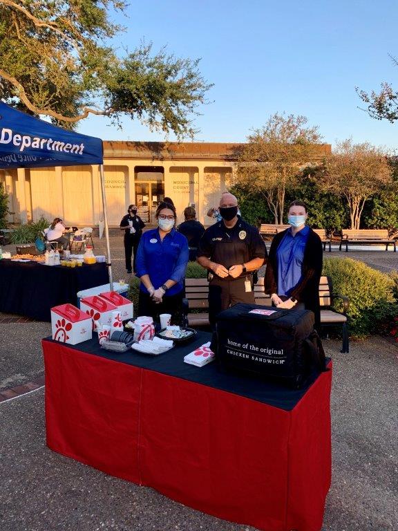 Police and Chik-fil-A staff stand near the Chik-fil-A booth in the City Hall courtyard