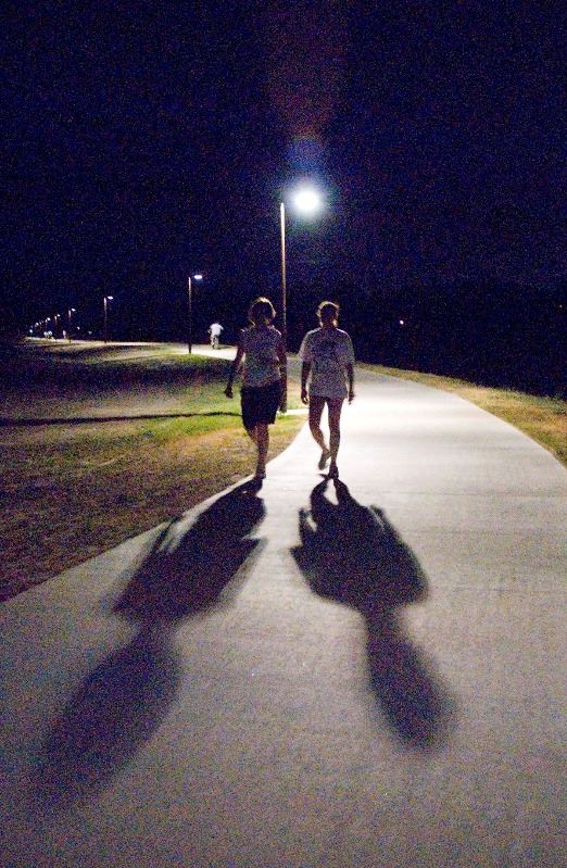 Two people walking along the Lone Tree Creek Hike and Bike Trail at night