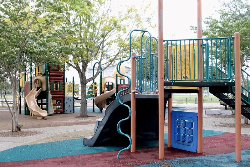 A playground structure with climbing pole, slide and other elements. Another structure behind it.