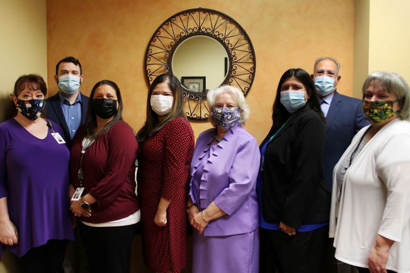 Finance employees wearing facial coverings pose for a group photo in the Finance lobby.