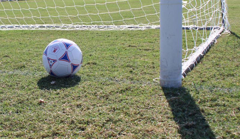 A soccer ball sits in a goal box.