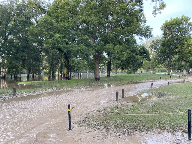 In Riverside Park, road is covered in silt and golf course in background is flooded