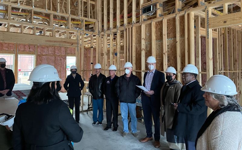 Several people in hard hats stand in an unfinished building