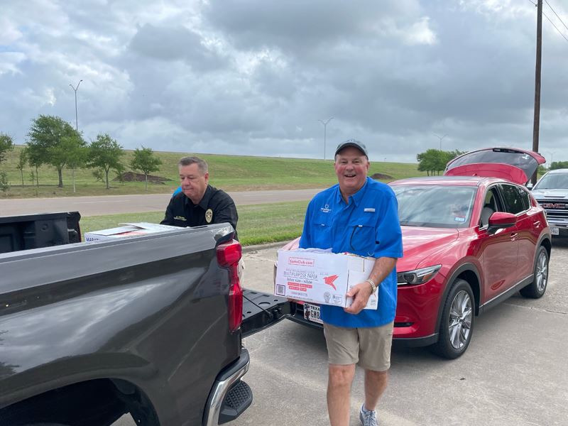 Two men unload cardboard boxes from the back of a pickup truck