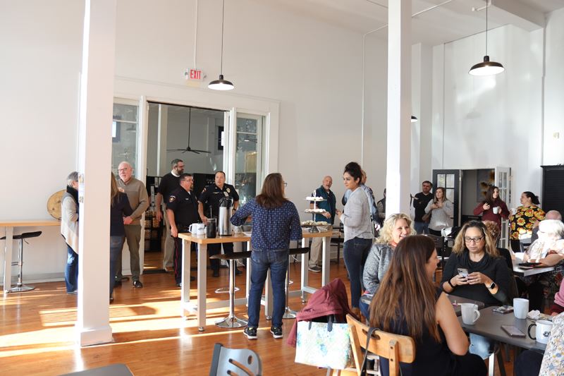 Many people talking and eating pastries in a dining area
