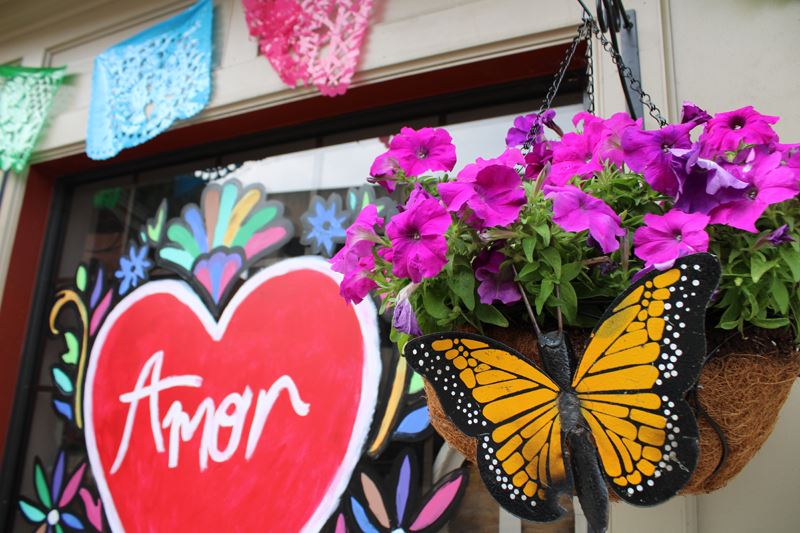 A decorative planter with a metal butterfly and a painted window nearby