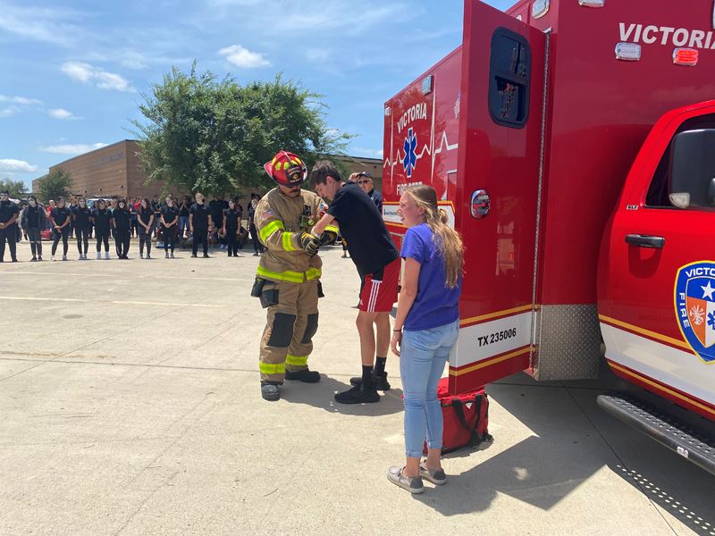 Firefighter assisting two teenagers outside an ambulance