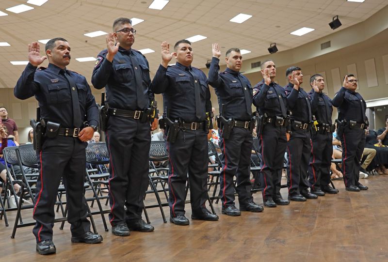 Eight uniformed police officers raise their right hands.