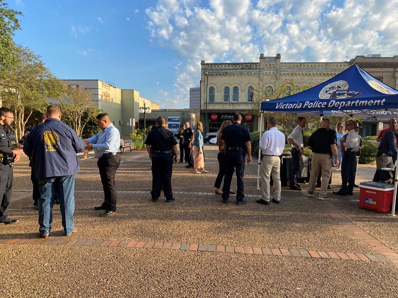 Several people mill around a courtyard with a Victoria Police Department canopy set up
