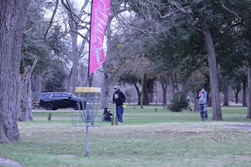 A disc golf player watches his shot near a goalpost.