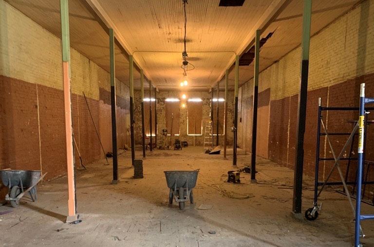 An empty building with plywood over windows and wheelbarrows and other construction equipment