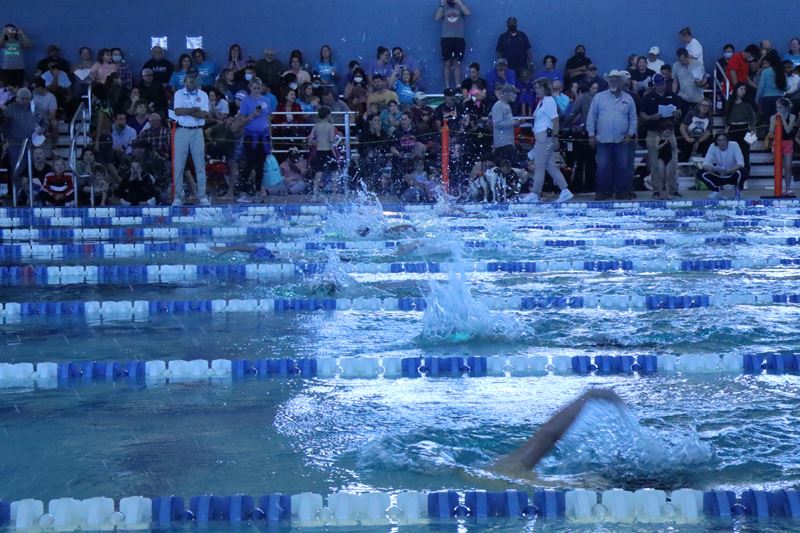 Swimmers race in lanes in a large indoor swimming pool
