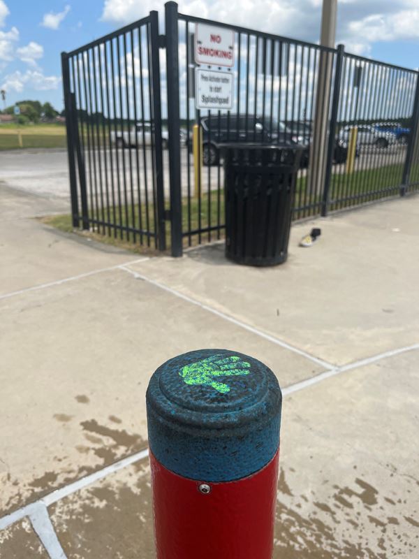 A short red pole with a blue button on top with an image of a green handprint
