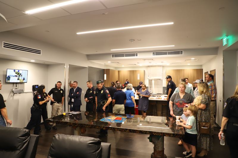 People gather around an ornate kitchen table with the Victoria Fire Department logo