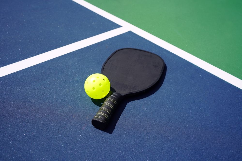 Pickleball paddle and ball on court