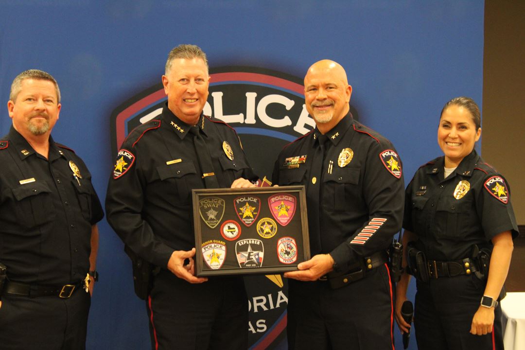 Police officers hold display case of patches