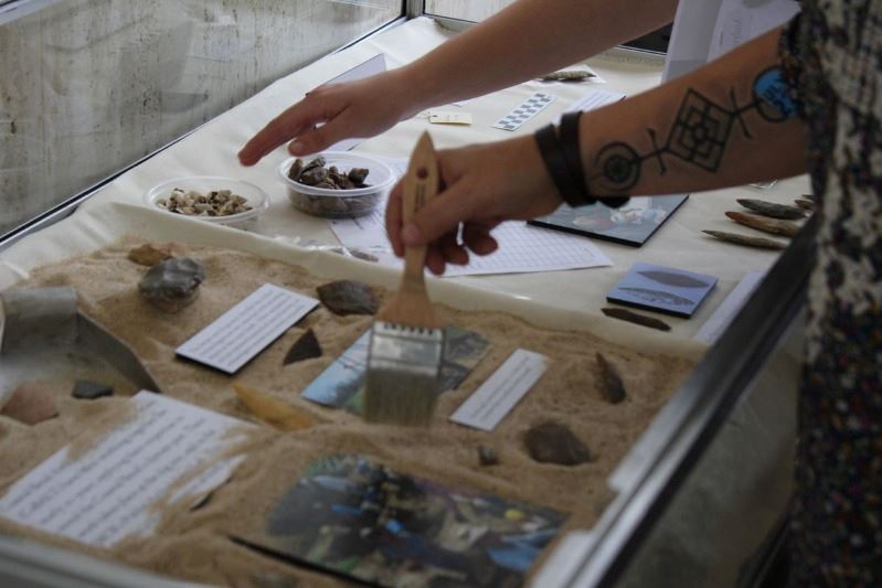 Woman brushes sand in glass case