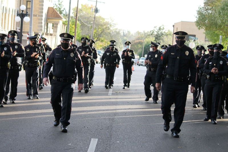 Crowd of masked police officers walk down street