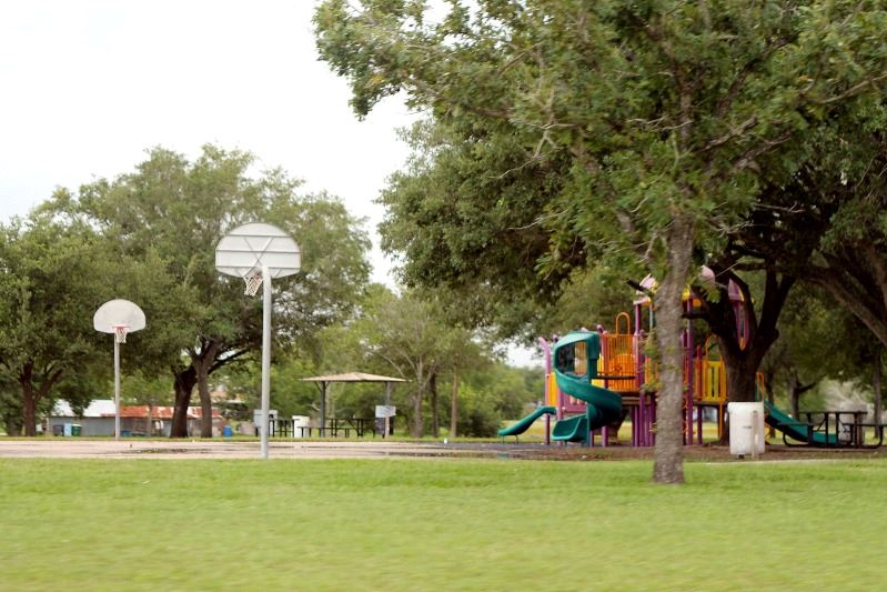 A small park with a basketball court, a children's playground and a pavilion.