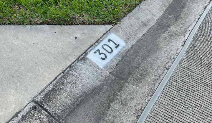 The numbers 3-0-1 are painted in black on a white background on a curb.