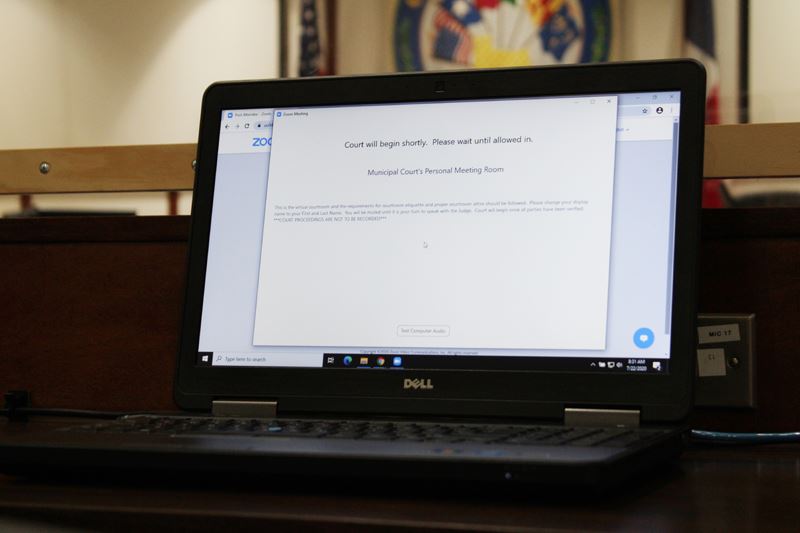 A laptop displays a Zoom waiting screen.