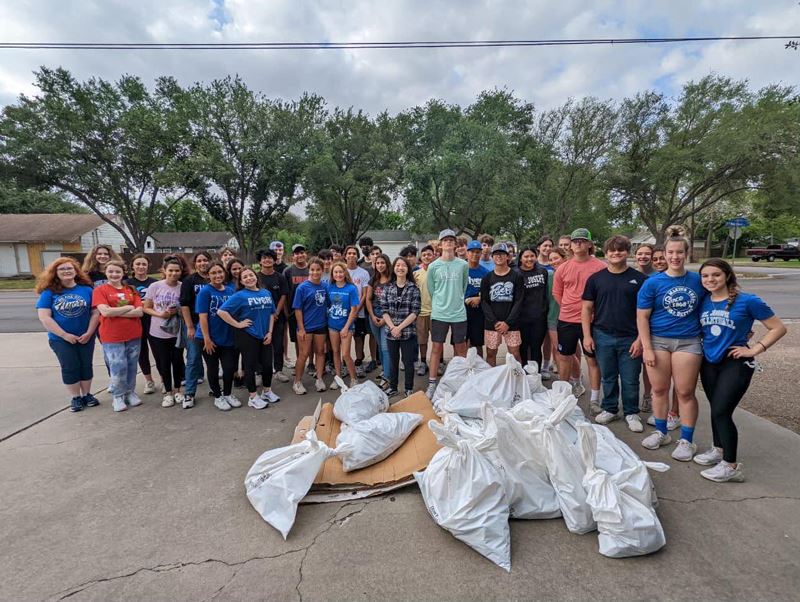 Large group of people posing with trash bags and other debris