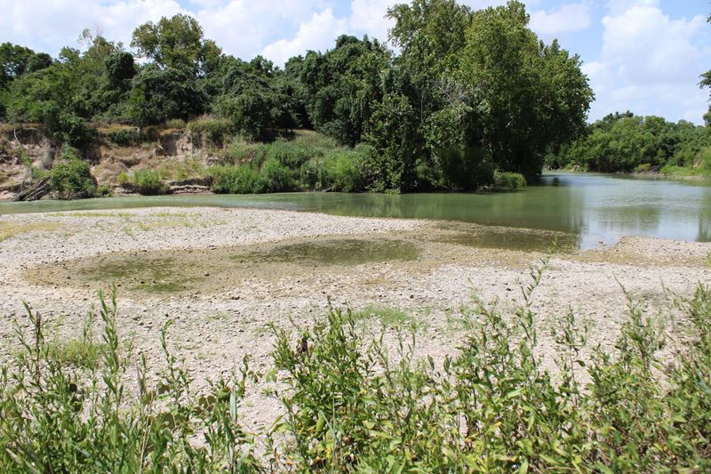 The Guadalupe River. Water has receded from a large patch of the river bed.